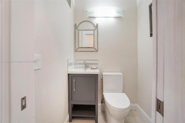 bathroom featuring baseboards, tile patterned flooring, toilet, and vanity