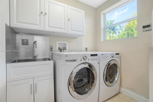 clothes washing area featuring light tile patterned flooring, baseboards, washer and clothes dryer, a sink, and cabinet space