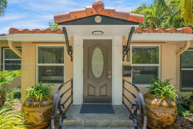 doorway to property with stucco siding and a tiled roof