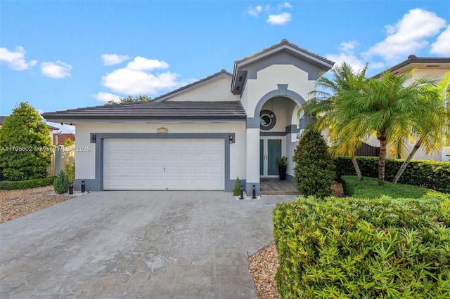 view of front of house with a garage, stucco siding, driveway, and a tiled roof