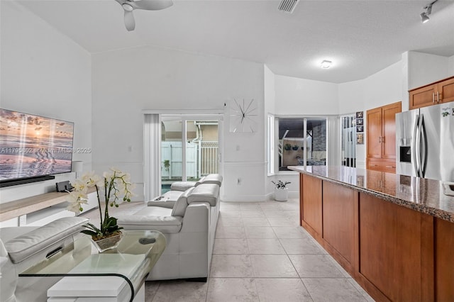 living area featuring a ceiling fan, light tile patterned flooring, lofted ceiling, and visible vents
