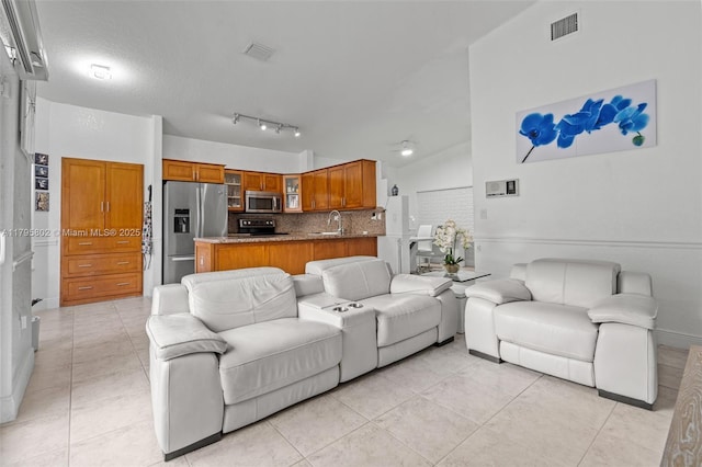 living area with light tile patterned flooring, baseboards, visible vents, and lofted ceiling