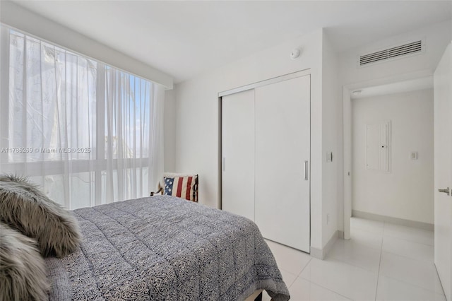 bedroom with baseboards, a closet, light tile patterned flooring, and visible vents