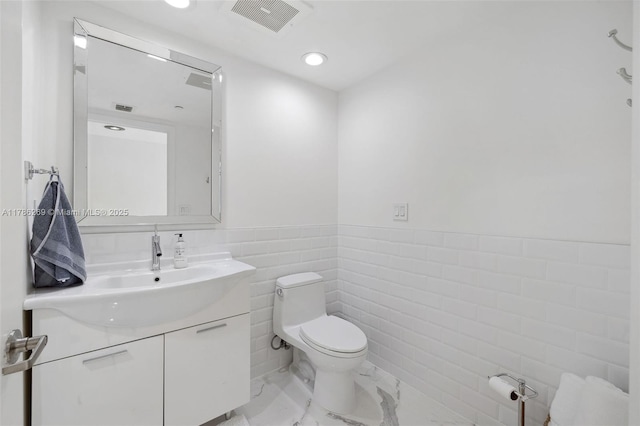 bathroom featuring visible vents, vanity, marble finish floor, toilet, and tile walls