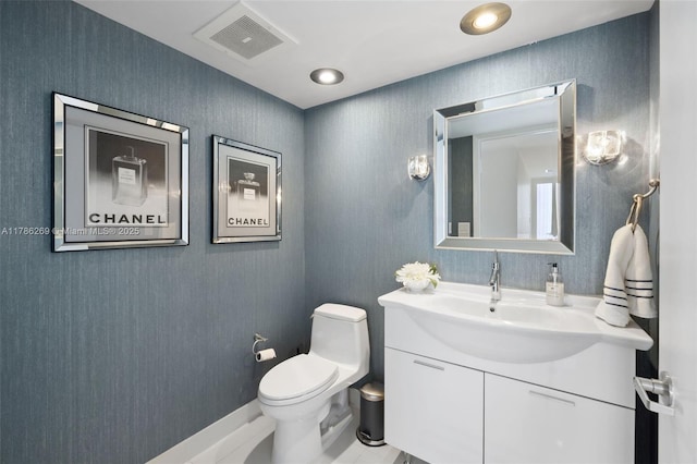 half bath with toilet, visible vents, and vanity