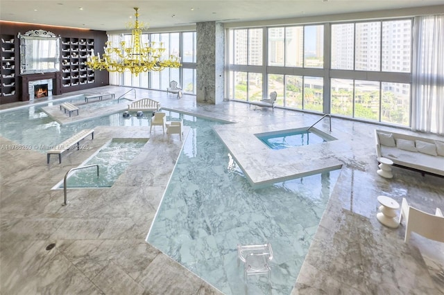 view of pool featuring an inviting chandelier and a warm lit fireplace