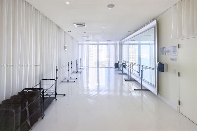 hall with baseboards, visible vents, concrete floors, and a wall of windows