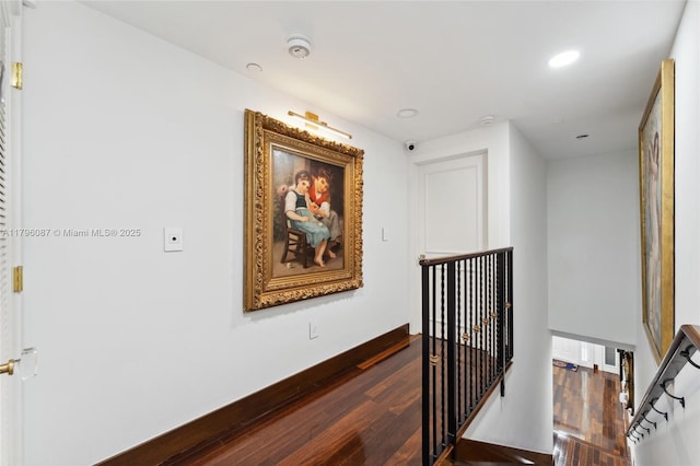 corridor with recessed lighting, dark wood-style flooring, baseboards, and an upstairs landing