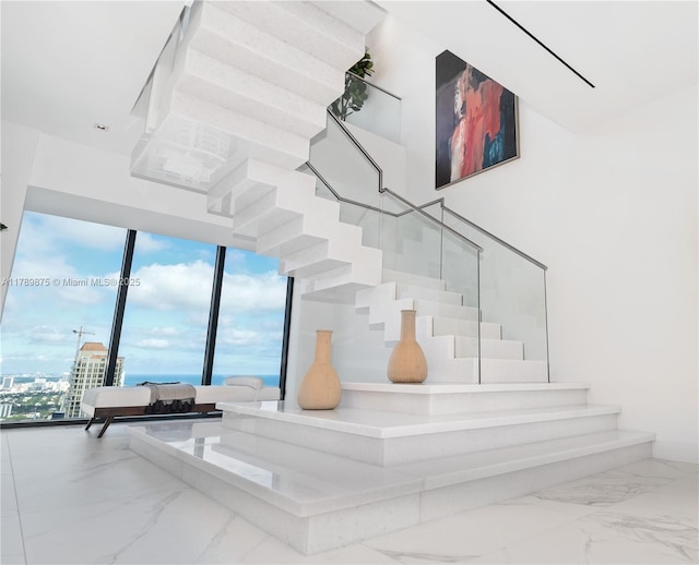 stairway with a towering ceiling and marble finish floor