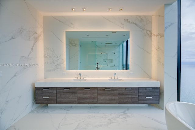 bathroom with a sink, double vanity, marble finish floor, and a freestanding bath