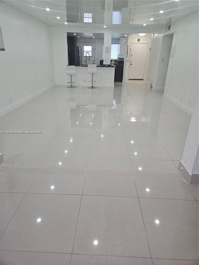 unfurnished room with light tile patterned floors, baseboards, and a sink
