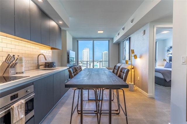 kitchen featuring tasteful backsplash, a sink, light countertops, black electric stovetop, and oven