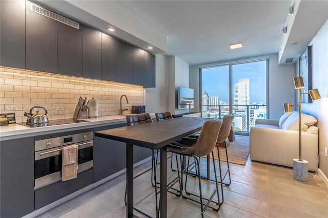 kitchen featuring backsplash, light countertops, black electric stovetop, open floor plan, and oven