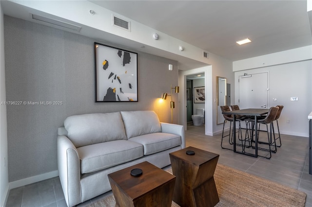 living area with baseboards, visible vents, and tile patterned flooring