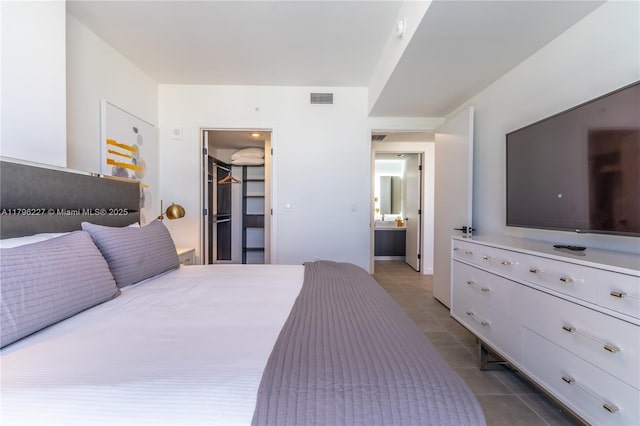 bedroom with dark tile patterned flooring, visible vents, a walk in closet, and a closet