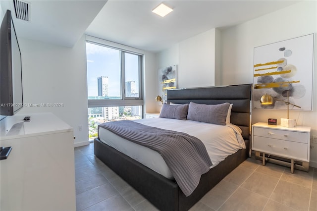 bedroom with a view of city, baseboards, visible vents, and tile patterned flooring