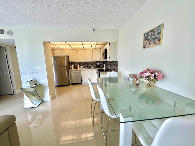 dining room with light tile patterned flooring, a textured ceiling, and visible vents