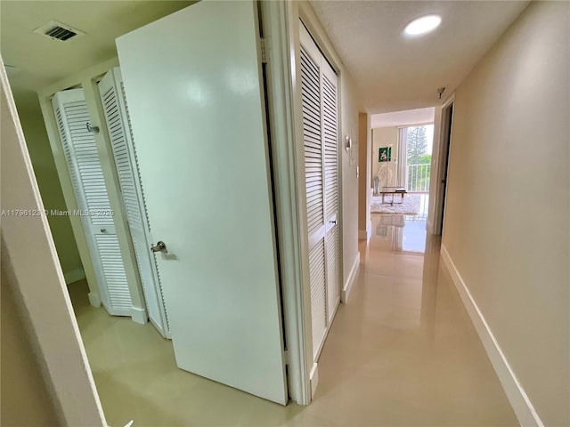 hallway featuring baseboards, recessed lighting, and visible vents