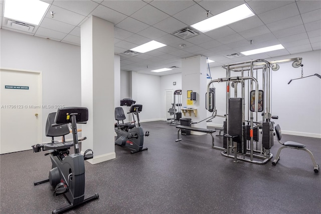 exercise room featuring baseboards, a drop ceiling, and visible vents
