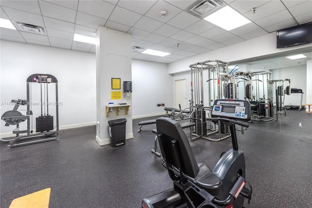 workout area with visible vents, a paneled ceiling, and baseboards