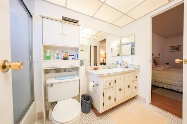 ensuite bathroom with vanity, ensuite bath, toilet, tile patterned floors, and a paneled ceiling