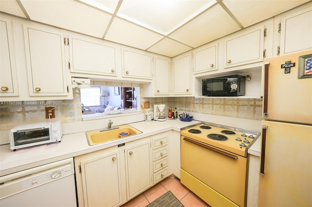 kitchen with a sink, white appliances, light countertops, light tile patterned floors, and tasteful backsplash