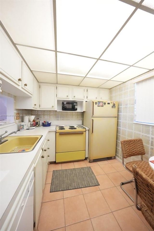 kitchen with white appliances, tile walls, light countertops, a sink, and light tile patterned floors