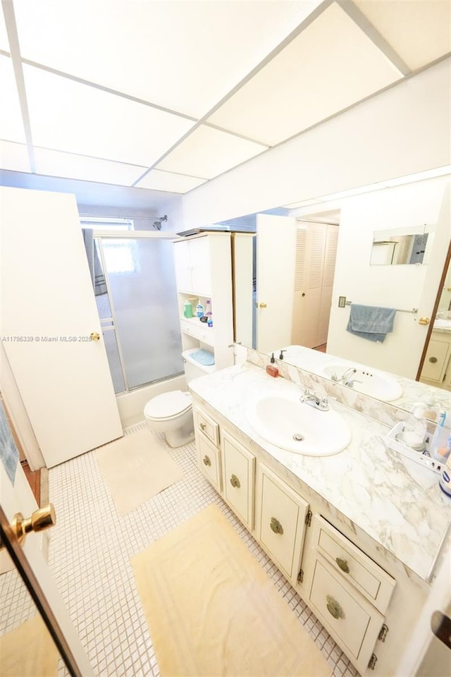 bathroom with toilet, enclosed tub / shower combo, tile patterned flooring, and vanity