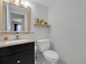 bathroom featuring toilet, tile patterned floors, baseboards, and vanity