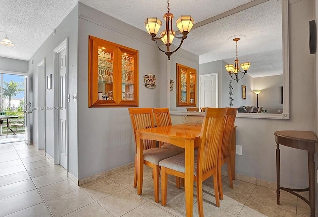 dining room featuring baseboards, a textured ceiling, light tile patterned floors, and a notable chandelier