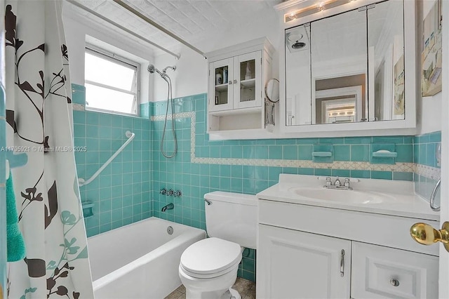 full bathroom featuring tile walls, wainscoting, vanity, toilet, and shower / tub combo with curtain