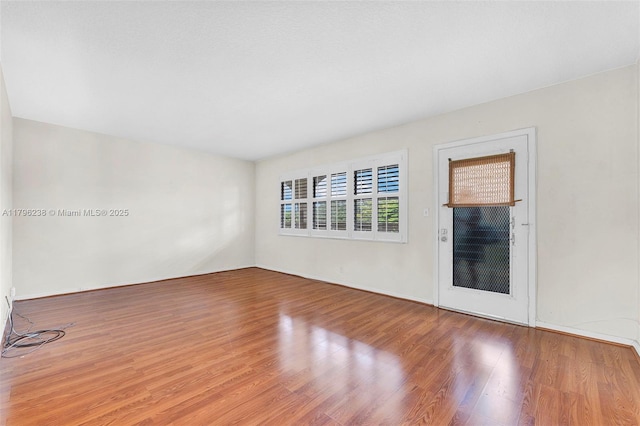 empty room with baseboards and wood finished floors