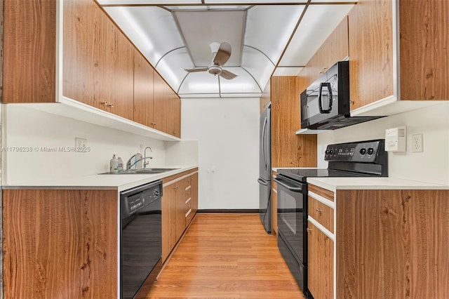 kitchen featuring a sink, light countertops, light wood-style flooring, a ceiling fan, and black appliances