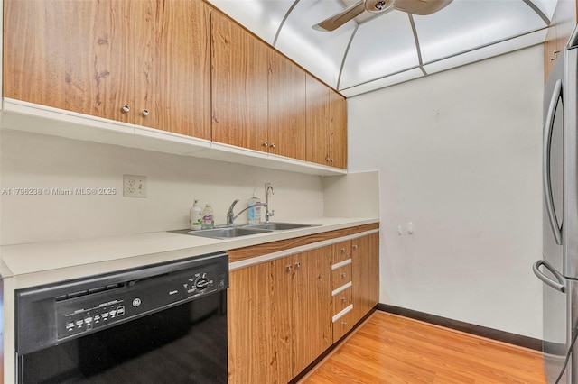 kitchen featuring dishwasher, a sink, baseboards, freestanding refrigerator, and light wood-style flooring