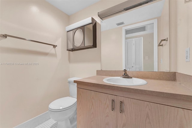 half bath with vanity, tile patterned floors, baseboards, and toilet