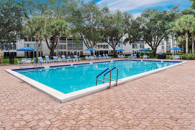 community pool with fence and a patio area