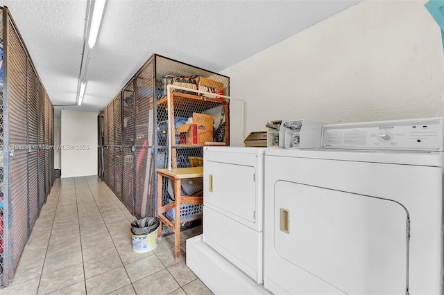 laundry room featuring washer and clothes dryer, a textured ceiling, and light tile patterned floors