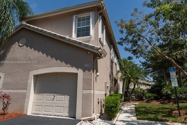 view of property exterior featuring a garage, aphalt driveway, and stucco siding