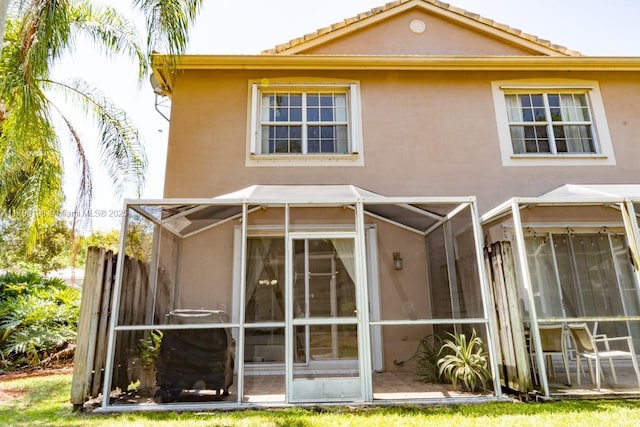 back of property with stucco siding and a sunroom