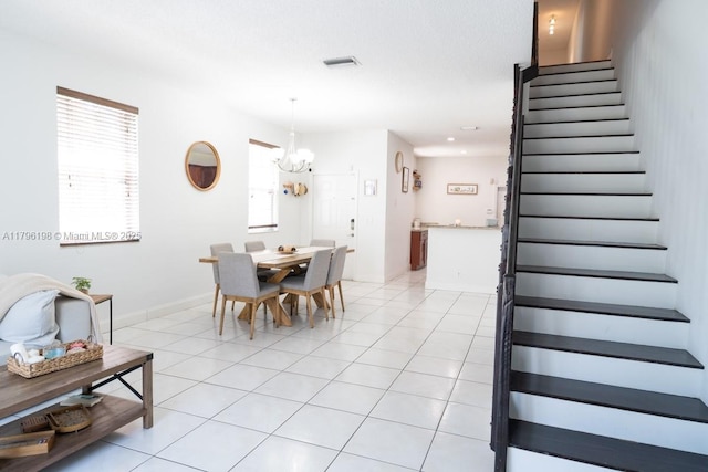 dining space with stairs, a chandelier, light tile patterned floors, and visible vents