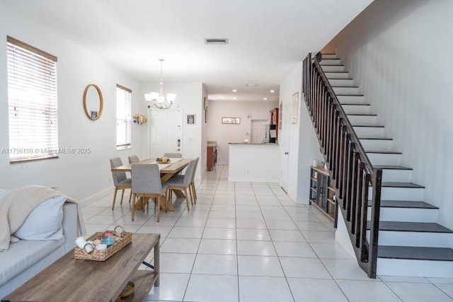 living room featuring light tile patterned flooring, a notable chandelier, baseboards, visible vents, and stairway