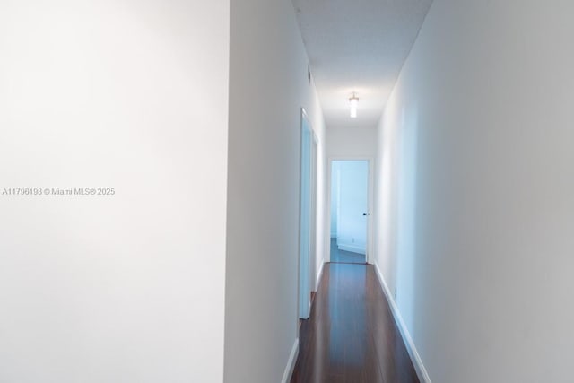 corridor with baseboards and dark wood-style floors