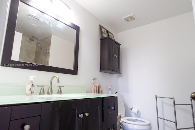 bathroom featuring visible vents, a tile shower, toilet, and vanity