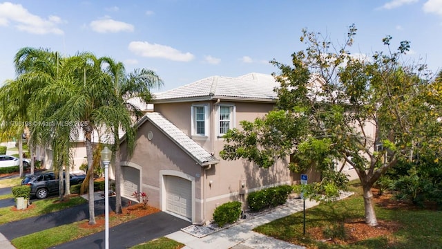 view of front facade with an attached garage, aphalt driveway, stucco siding, and a tile roof
