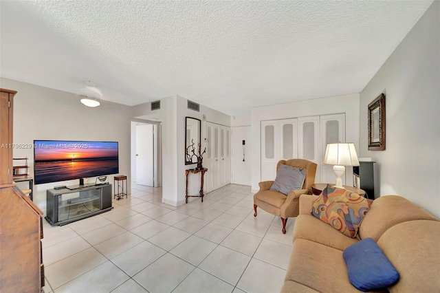 living area featuring a textured ceiling, light tile patterned flooring, and visible vents