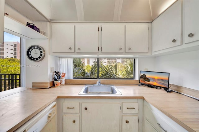 kitchen with light countertops, white cabinets, a sink, and dishwasher