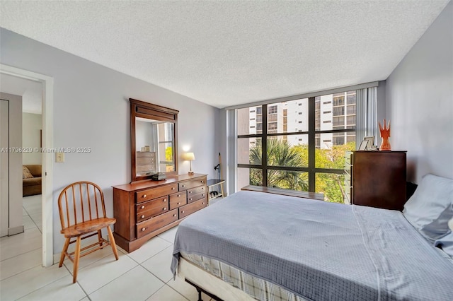bedroom with light tile patterned floors, a wall of windows, and a textured ceiling