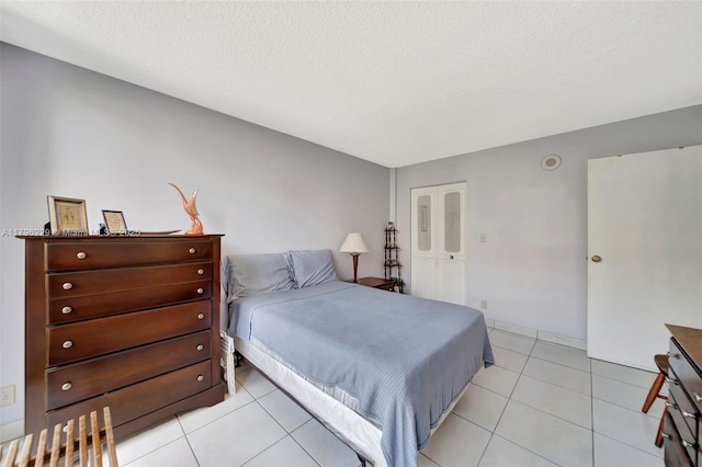 bedroom with a textured ceiling and light tile patterned floors