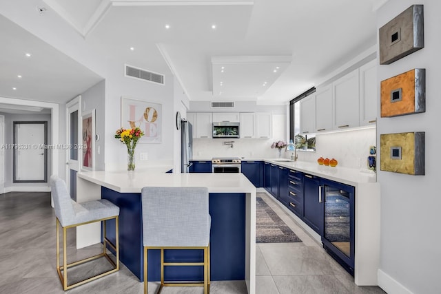 kitchen featuring visible vents, a peninsula, beverage cooler, appliances with stainless steel finishes, and blue cabinetry