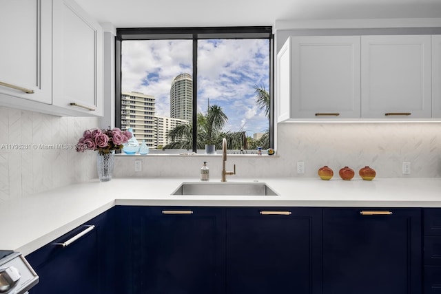 kitchen featuring light countertops, decorative backsplash, a sink, and blue cabinets